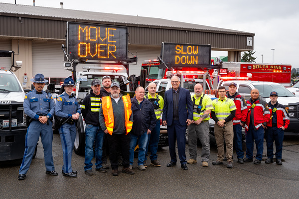 Gov. Jay Inslee takes a picture with roadside safety workers and their equipment