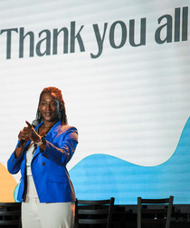 Megan Matthews, the Director of Office of Equity, standing in front of a slide that says "Thank you all!"