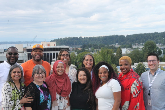 A group of people sit in front of a skyline smiling at the camera.