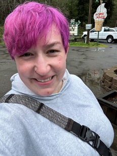 Beth Chapin smiling for a selfie with purple dyed hair in front of a home-made ice cream stand