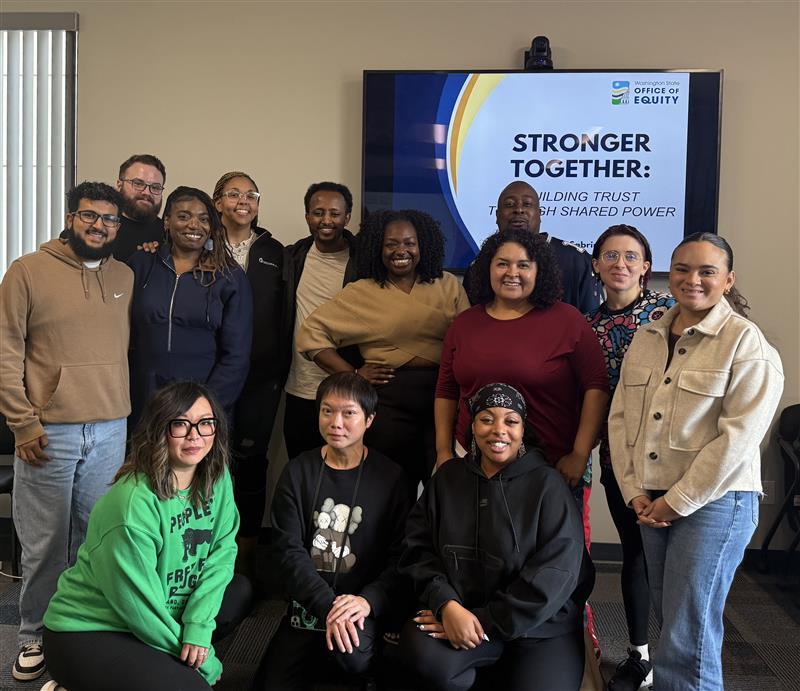 2025 CAB In-Person Retreat. 13 people pose for a photo in front of the text "Stronger Together."