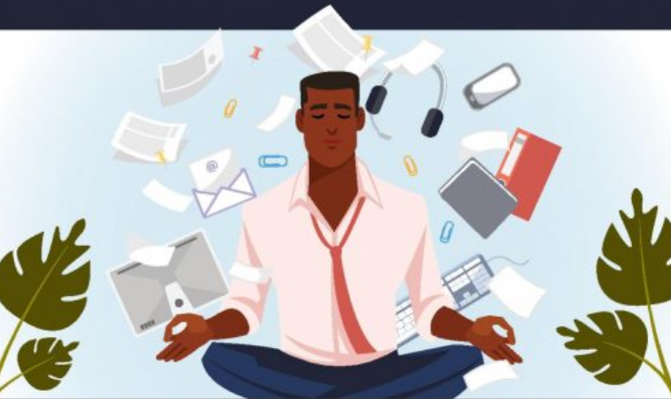 A man meditating among many work stressors, including a computer, emails, work phone, files, and more.