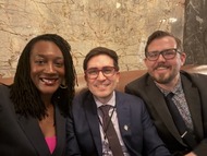 Three people smile for a selfie in formal attire.