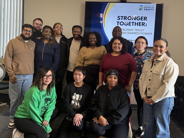 Picture of Community Advisory Board members and Program Managers in front of a presentation screen 