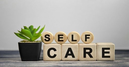 Letters blocks spelling out self care on table with green plant