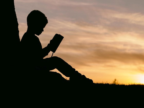 silhouette boy reading - Photo by Aaron Burden on Unsplash