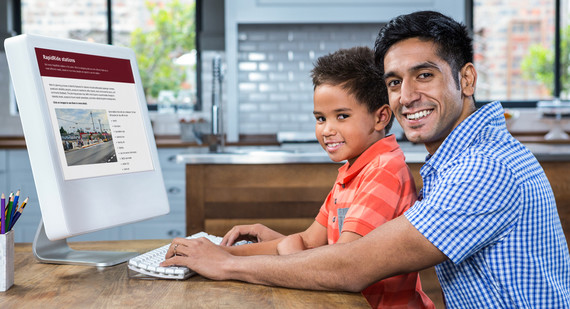 Picture of a father and son sitting at a desk looking at information online about the new RapidRide I Line