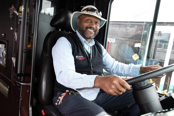 Metro bus driver, smiling with his hands on the steering wheel