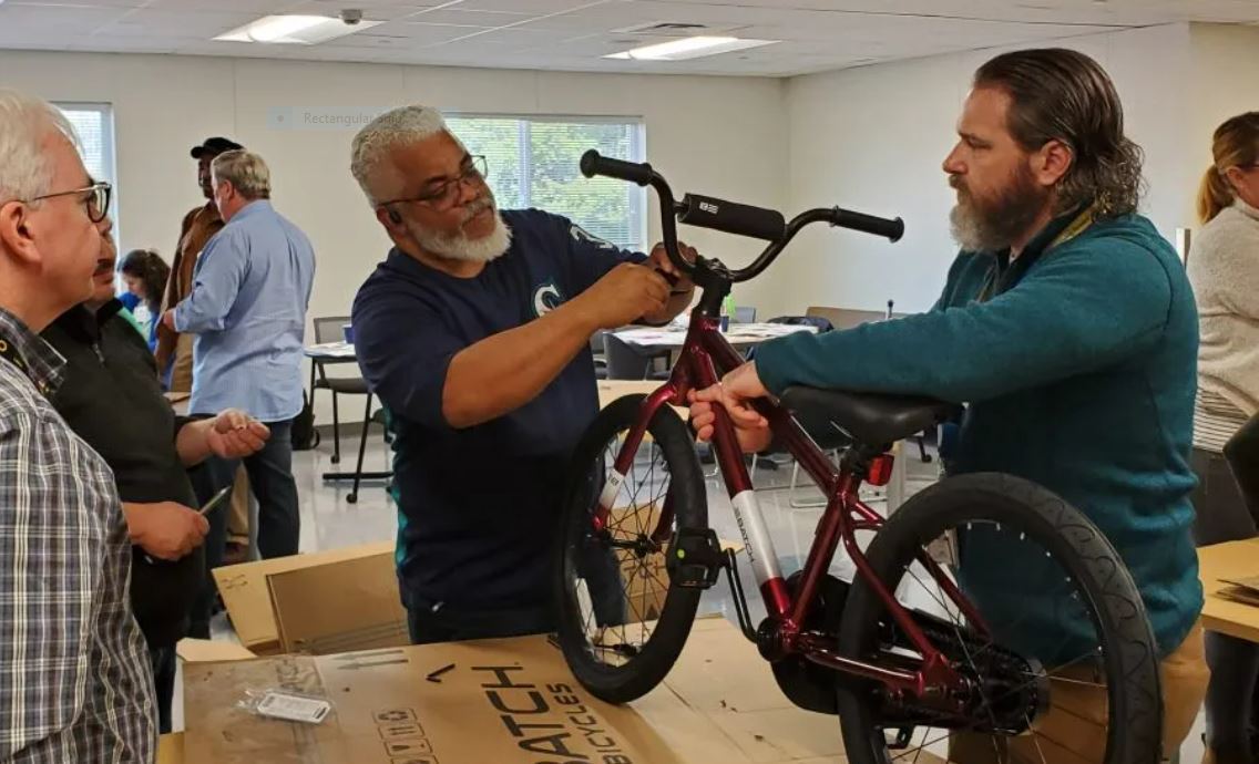 Metro employees working together using hand tools to assemble bicycles