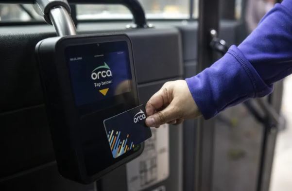 Image of a person tapping their new black ORCA card on the new ORCA reader inside the Metro bus