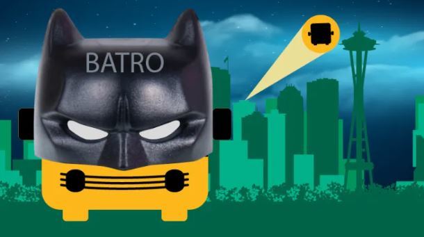 Image of Metro Avatar with Batman mask in from of green Seattle skyline and spotlight of Metro