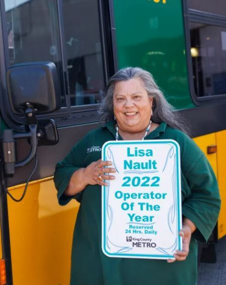 Photo of Operator Lisa Nault in front of Metro coach holding her Operator of the Year award.