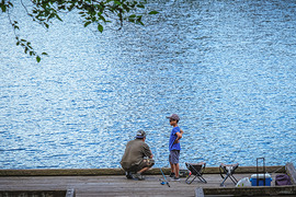 a boy and man fishing on the dock at Lake Geneva with blue water in the background