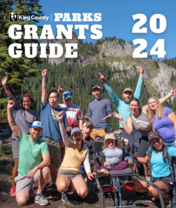 2024 Parks Grants Guide Cover - A group of hikers celebrate by an alpine lake