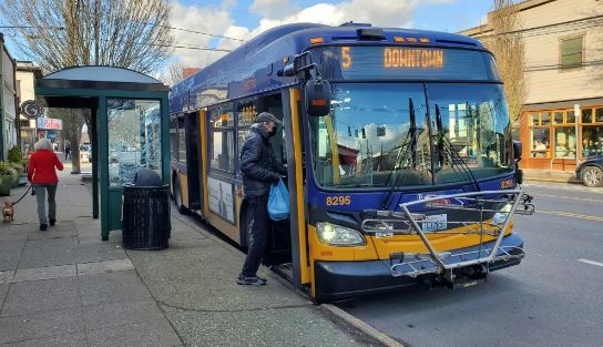 Route 5 bus boarding the bus next to a bus stop with a bus shelter