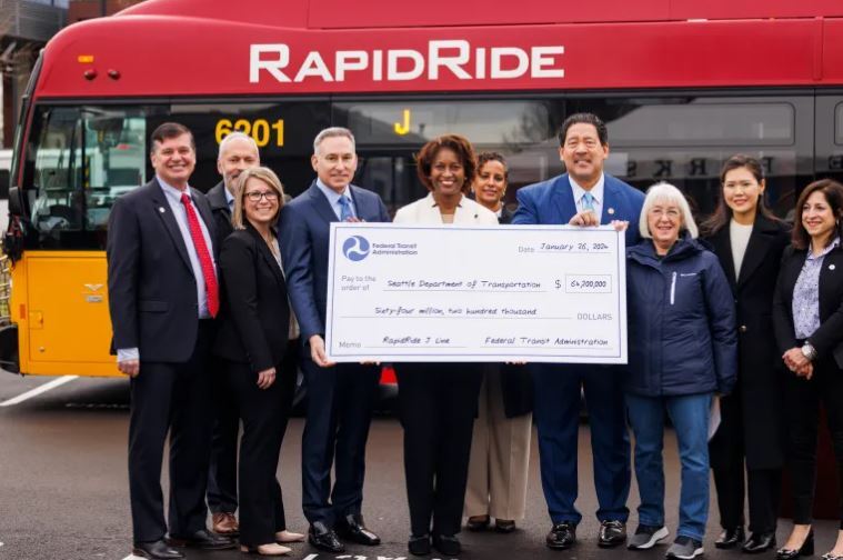 image of a future RapidRide J Line coach and many officials holding a giant check from FTA  