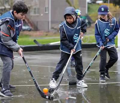 Three kids playing street hockey in the rain