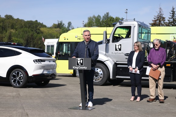 Executive Constantine delivers remarks in front of electric vehicles. 