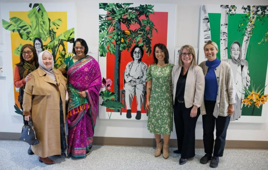 Picture shows Metro employees in front of large multi-panel installation by Linh Hoang and Keiko Budech.