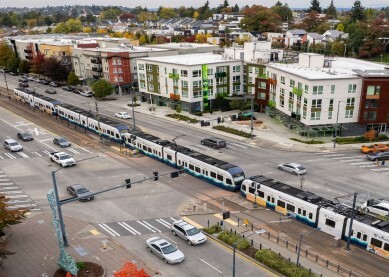 A light rail train crosses an intersection across a road