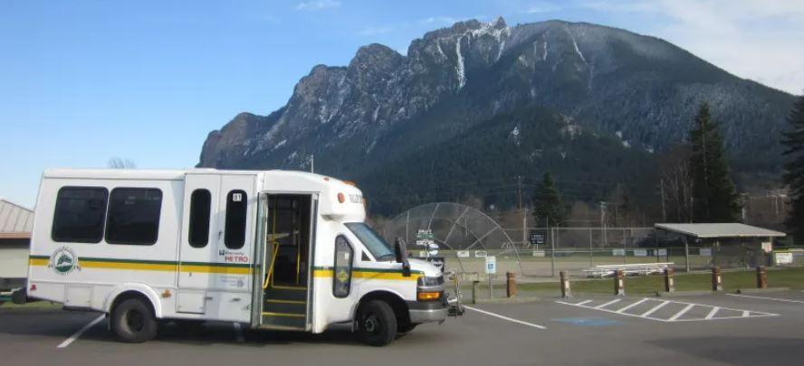 Snoqualmie Valley Transit shuttle in parking lot with baseball field and mountain in background