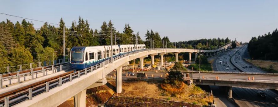 Link light rail traveling next to and above freeway during sunset