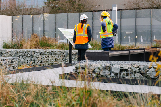 People in safety gear look over a sign while touring a rain garden at the Georgetown Wet Weather Station.