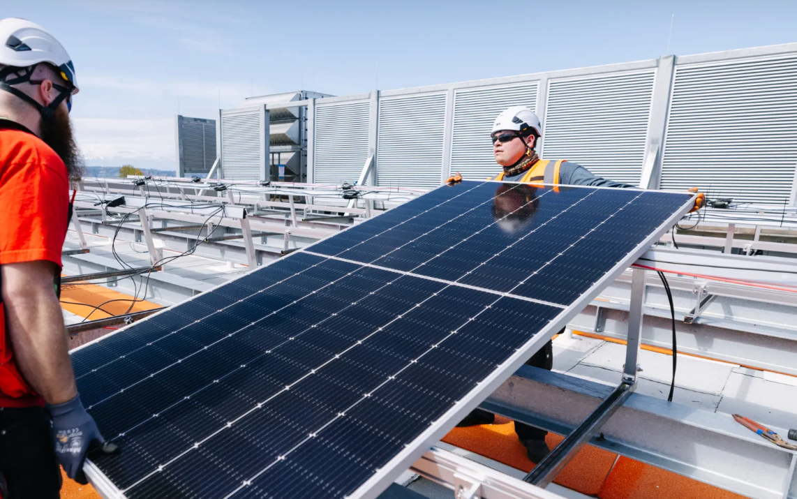 Staff set a solar panel in place on the roof of the Power Quality Improvement Project building at West Point Treatment Plant. 