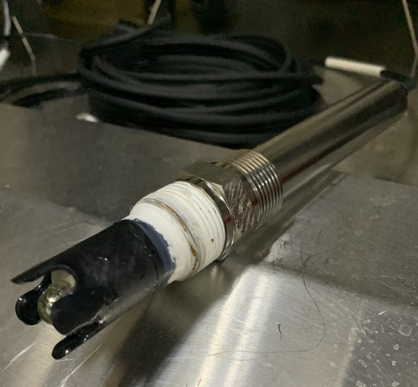 Photo shows a probe, a silver pipe with black and white tip attached to a black hose.