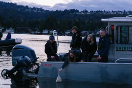 A woman uses a net to release kokanee salmon from a boat into the water.