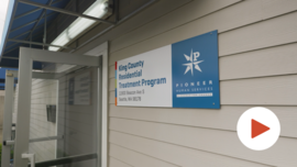 The front door of the King County Residential Treatment Program building, with an illustration of a video play button.