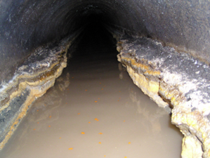 A thick layer of gunky fats, oil, and grease line the inside of a sewer pipe. 