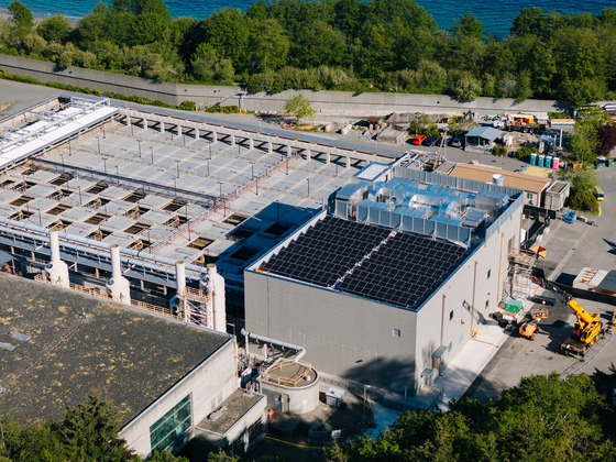 Aerial view of West Point Treatment Plant with solar panels, industrial structures, and equipment. Trees and water are visible in the background.