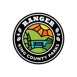 Text reads "King County Parks Ranger" with a drawing of mountains with the sun behind it. In the forefront is a paved trail leading to the mountains