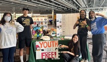 Four young people standing next to a Metro table
