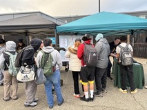 Students wearing backpacks standing next to a table