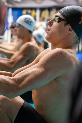 Photo of swimmers hanging on the edge of a pool waiting for a race to start