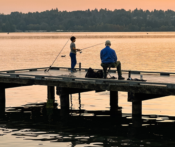 Two people on a dock with fishing poles.