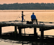 Man and young child fishing off a dock at sunset.