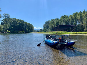 Inflatable boat in the Snoqualmie River with trees and blue sky in the background