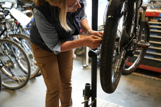 Volunteer repairs bike at the Shoreline Tool Library with more bikes in the background