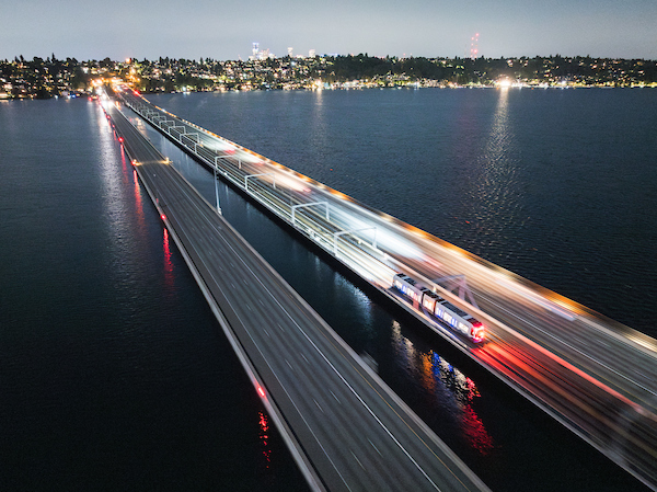 Light rail cars drive along the I-90 bridge towards the Eastside at night