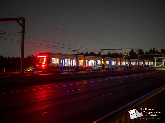A light rail train crosses I-90 in the dark