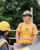 A King County employee in a hard hat and orange safety shirt talks with coworkers at a treatment facility.
