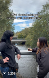 Two people talk to each other while on a bridge overlooking Cedar River
