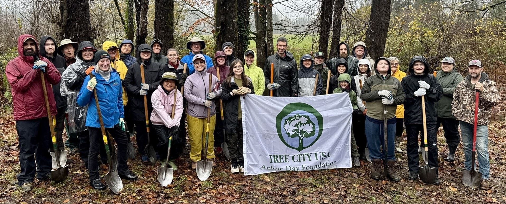 Photo of a group of people holding shovels with a banner saying “Tree City USA”