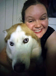 White female with brown hair hugging a white and tan large dog 