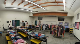 A room filled with racks of clothes and tables with clothing and shoes on them