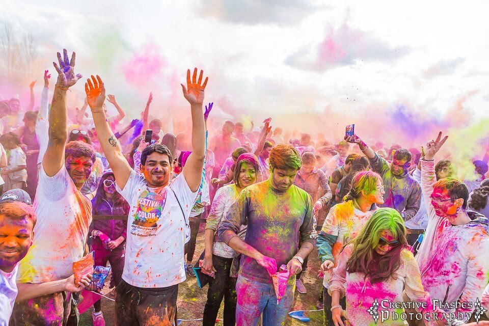 A crowd of people celebrating as colored powder fills the air
