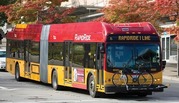 A red and yellow articulated bus with "RapidRide I Line" text on the front, carrying a bicycle on a rack. 